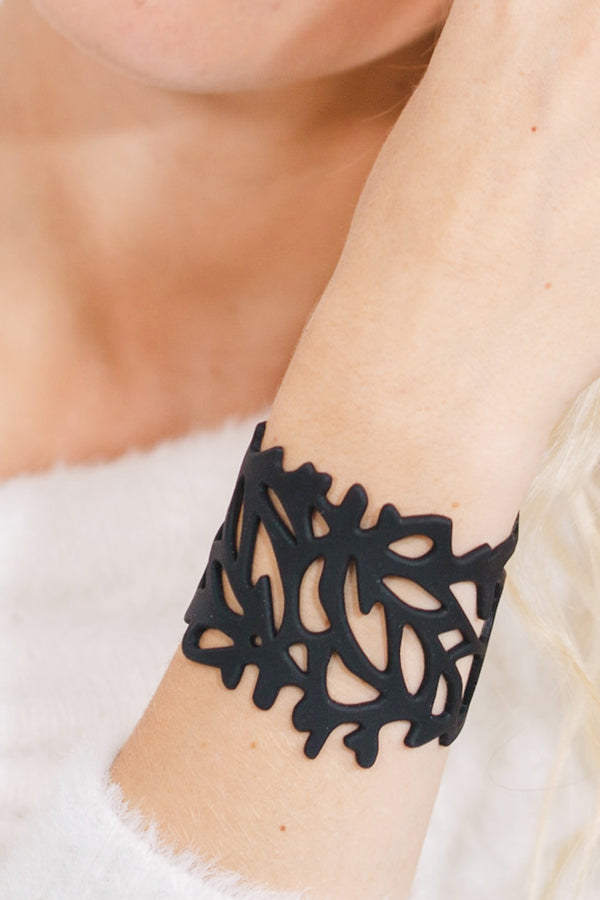 zoom, vue gros plan, bracelet corail, couleur noir. Vue taille réelle, porté sur poignet par mannequin Dorine Gaudin. Bijoux fantaisies en silicone, ladygum, marque française, créateurs, designers. Style nature, manchette femme, ajouré, algues, mer. Léger, souple, longueur réglable, bracelet ajustable, fermoir en T, résistant à l'eau, à la chaleur, à la lumière, minimisant les allergies. Cadeau original.