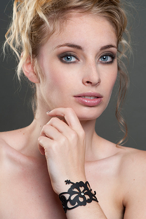 vue détails, gros plan, bracelet hibiscus, couleur noir, porté par mannequin, poignet. Silicone, bijoux fantaisies, ladygum, marque française, créateurs, designers. Style été, plage, nature, fleur, floral, tropique, tropical, jasmin, exotique, îles, manchette. Souple, léger, longueur réglable, bracelet ajustable, fermoir en T. Résistant à l'eau, à la lumière, à la chaleur, minimisant les allergies.