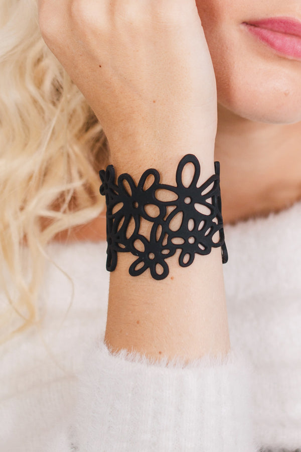 zoom, vue gros plan, bracelet hippie, couleur noir. Vue taille réelle, porté sur poignet par mannequin Dorine Gaudin. Bijoux fantaisies en silicone, ladygum, marque française, créateurs, designers. Style manchette femme, nature, fleur, floral, paquerette, marguerite, année 70. Léger, souple, longueur réglable, bracelet ajustable, fermoir en T, résistant à l'eau, à la chaleur, à la lumière, minimisant les allergies. Cadeau original.