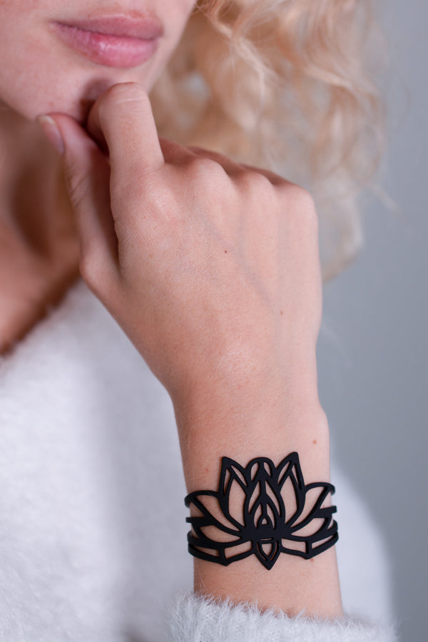 vue gros plan, détails, bracelet mantra, noir, silicone, porté sur mannequin, dorine gaudin. Ladygum, bijoux fantaisies, créateurs, designers, marque française. Style manchette, zen, fleur, floral, indien, nature, feuilles, lotus. Souple, léger, minimisant les allergies, longueur réglable, fermoir en T, résistant à l'eau, à la chaleur, à la lumière.