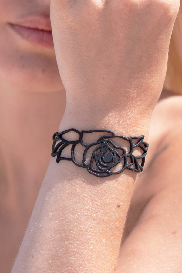 zoom, vue gros plan, bracelet rose, couleur noir. Vue taille réelle, porté sur poignet par mannequin Dorine Gaudin. Bijoux fantaisies en silicone, ladygum, marque française, créateurs, designers. Style nature, manchette femme, fleur, amour, romantique, feuille. Léger, souple, longueur réglable, bracelet ajustable, fermoir en T, résistant à l'eau, à la chaleur, à la lumière, minimisant les allergies. Cadeau original.