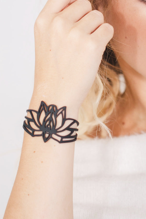 zoom, vue gros plan, bracelet mantra, couleur noir. Vue taille réelle, porté sur poignet par mannequin Dorine Gaudin. Bijoux fantaisies en silicone, ladygum, marque française, créateurs, designers. Style nature, manchette femme, fleur, floral, zen, lotus, nénuphar, yoga, feuille, plante. Léger, souple, longueur réglable, bracelet ajustable, fermoir en T, résistant à l'eau, à la chaleur, à la lumière, minimisant les allergies. Cadeau original.