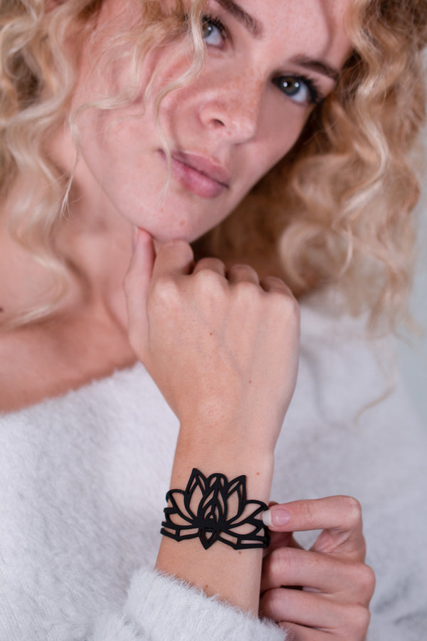 vue gros plan, détails, bracelet mantra, noir, silicone, porté sur mannequin, dorine gaudin. Ladygum, bijoux fantaisies, créateurs, designers, marque française. Style manchette, zen, fleur, floral, indien, nature, feuilles, lotus. Souple, léger, minimisant les allergies, longueur réglable, fermoir en T, résistant à l'eau, à la chaleur, à la lumière.