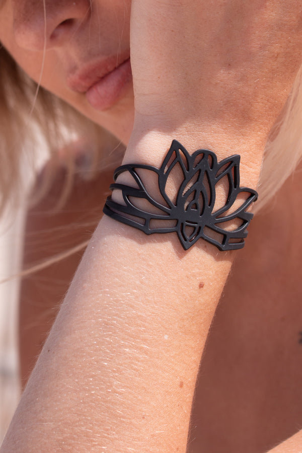 zoom, vue gros plan, bracelet mantra, couleur noir. Vue taille réelle, porté sur poignet par mannequin Dorine Gaudin. Bijoux fantaisies en silicone, ladygum, marque française, créateurs, designers. Style nature, manchette femme, fleur, floral, zen, lotus, nénuphar, yoga, feuille, plante. Léger, souple, longueur réglable, bracelet ajustable, fermoir en T, résistant à l'eau, à la chaleur, à la lumière, minimisant les allergies. Cadeau original.