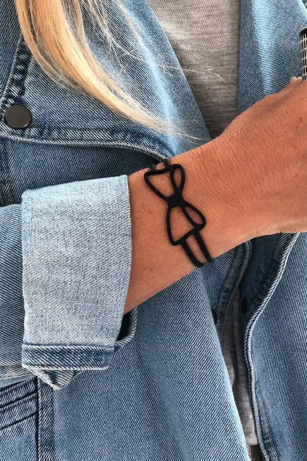 vue bracelet noeud, noir, silicone, gros plan, taille réelle, porté par la créatrice Morgane. Bijoux fantaisies, ladygum, marque française, créateurs, designers. Style minimaliste, féminin, noeud papillon, ruban, fille, couture. Léger, souple, longueur réglable, bracelet ajustable, fermoir en T.