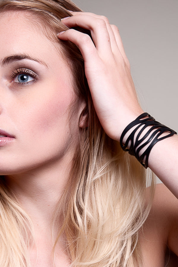 vue gros plan, taille réelle, bracelet safari, couleur noir, porté par mannequin. Silicone, bijoux fantaisies, ladygum, marque française, créateurs, designers. Style été, plage, nature, jungle, ethnique, tribal, manchette. Souplé, léger, longueur réglable, bracelet ajustable, fermoir en T. Résistant à l'eau, à la lumière, à la chaleur, minimisant les allergies.