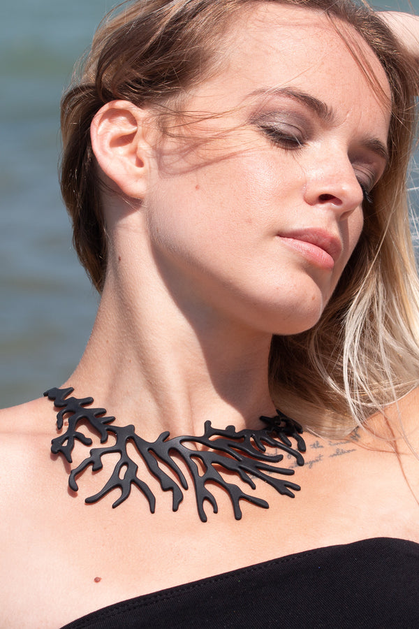 zoom, vue gros plan, collier corail, couleur noir, dispo en rouge/corail. Vue taille réelle, porté par mannequin dorine gaudin. Bijoux fantaisies en silicone, ladygum, marque française, créateurs, designers. Style plastron, algues, mer, plante, feuille, nature. Léger, souple, résistant à l'eau/à la chaleur/à la lumière. Collier ajustable, longueur réglable, fermoir en T. Cadeau original.