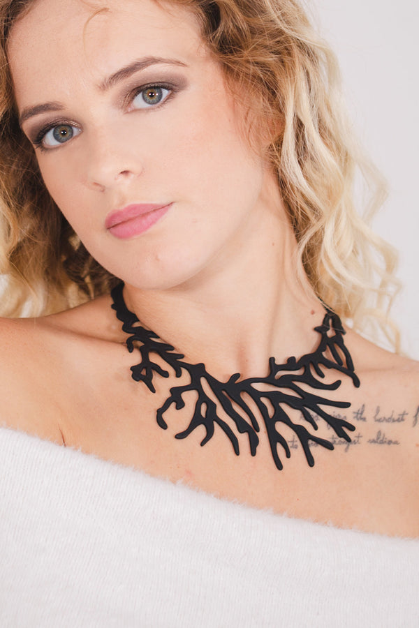 zoom, vue gros plan, collier corail, couleur noir, dispo en rouge/corail. Vue taille réelle, porté par mannequin dorine gaudin. Bijoux fantaisies en silicone, ladygum, marque française, créateurs, designers. Style plastron, algues, mer, plante, feuille, nature. Léger, souple, résistant à l'eau/à la chaleur/à la lumière. Collier ajustable, longueur réglable, fermoir en T. Cadeau original.