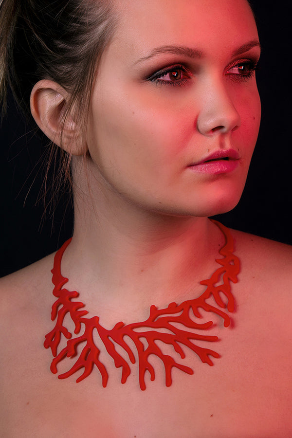 zoom, vue gros plan, collier corail, couleur rouge. Vue taille réelle, porté par mannequin maureen, miss belgique. Bijoux fantaisies en silicone, ladygum, marque française, créateurs, designers. Style plastron, algues, mer, plante, feuille, nature. Léger, souple, résistant à l'eau/à la chaleur/à la lumière. Collier ajustable, longueur réglable, fermoir en T. Cadeau original.
