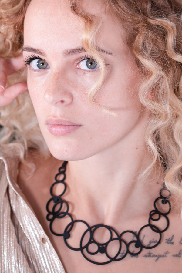 vue collier disco,taille réelle, porté sur mannequin, dorine gaudin. Ladygum, bijoux fantaisies, marque française, créateurs, designers. Silicone, disponible en noir. Style rond, cercle, bulle, années 70, seventies, hippie. Minimisant les allergies, léger, souple, longueur réglable, bijou ajustable, résistant à l'eau et à la chaleur. Modèle disco.