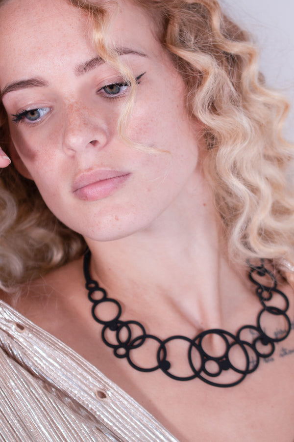 vue collier disco,taille réelle, porté sur mannequin, dorine gaudin. Ladygum, bijoux fantaisies, marque française, créateurs, designers. Silicone, disponible en noir. Style rond, cercle, bulle, années 70, seventies, hippie. Minimisant les allergies, léger, souple, longueur réglable, bijou ajustable, résistant à l'eau et à la chaleur. Modèle disco.