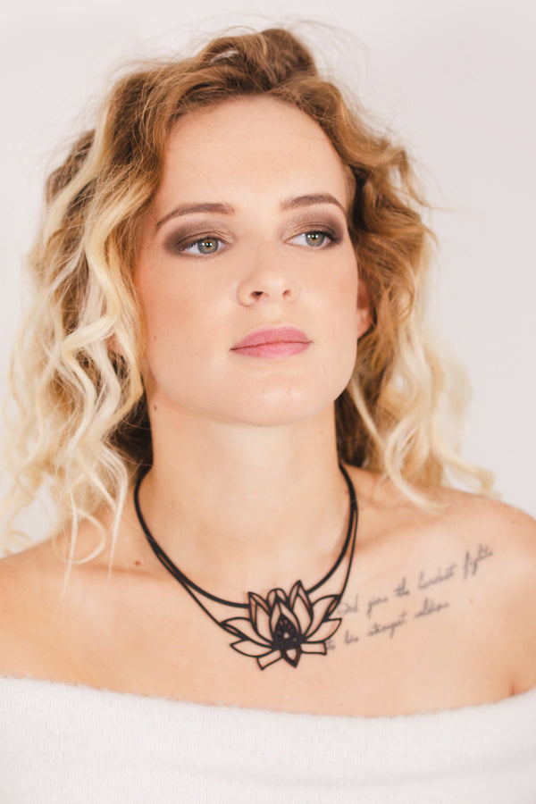 zoom, vue gros plan, collier mantra, couleur noir. Vue taille réelle, porté par mannequin dorine gaudin. Bijoux fantaisies en silicone, ladygum, marque française, créateurs, designers. Style plastron, fleur, nature, floral, lotus, nénuphar, zen, yoga, pétales, feuilles. Léger, souple, résistant à l'eau/à la chaleur/à la lumière. Collier ajustable, longueur réglable, fermoir en T. Cadeau original.