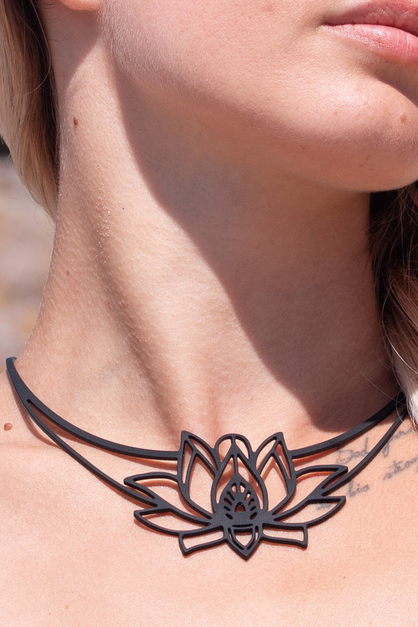 zoom, vue gros plan, collier mantra, couleur noir. Vue taille réelle, porté par mannequin dorine gaudin. Bijoux fantaisies en silicone, ladygum, marque française, créateurs, designers. Style plastron, fleur, nature, floral, lotus, nénuphar, zen, yoga, pétales, feuilles. Léger, souple, résistant à l'eau/à la chaleur/à la lumière. Collier ajustable, longueur réglable, fermoir en T. Cadeau original.