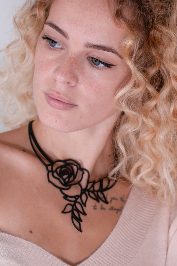 vue collier rose, taille réelle, porté par mannequin, dorine gaudin. Silicone, noir, ladygum, marque française, bijoux fantaisies, créateurs, designers. Style fleur, floral, romantique, amour. Minimisant les allergies, résistant à l'eau, à la chaleur, léger, souple, longueur réglable, ajustable, fermoir en T. Modèle Rose, long, plongeant.