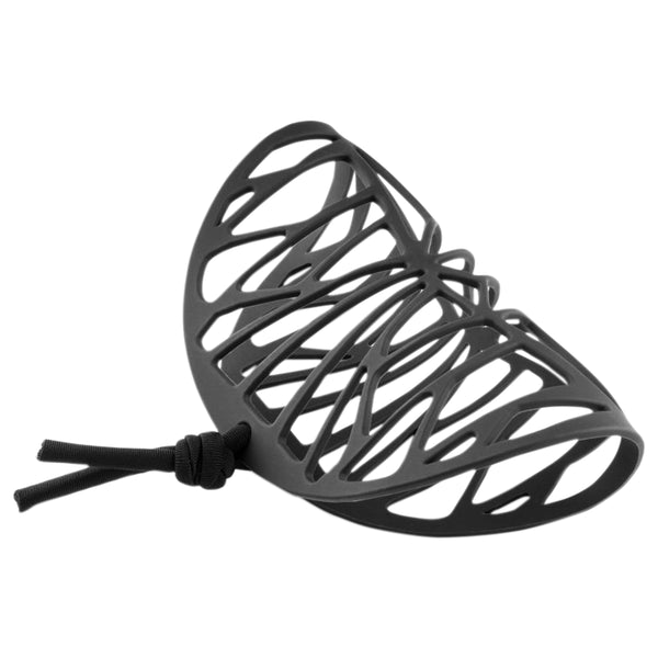 vue gros plan, de profil, manchette femme graphique, couleur noir. Bijoux fantaisies en silicone, marque française, créateurs, designers. Style géométrique, losange, triangle, ajouré, motif. Souple, léger, à mémoire de forme, résistant à l'eau/à la chaleur/à la lumière, minimisant les allergies. Vue du cordon en spandex, lyvra noir, réglable, ajustable. Cadeau original.