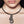 zoom, vue gros plan, collier pendentif hibiscus long, couleur noir. Vue taille réelle. Bijoux fantaisies en silicone, ladygum, marque française, créateurs, designers. Style simple, minimaliste. Collier simplissimo avec strass sawarovski, cristal, amovible, riveté. Pendentif hibiscus long, fleur, nature, floral, rond, cercle, boucle, tourbillon, exotique, tropical. Léger, souple, résistant à l'eau/à la chaleur/à la lumière. Collier ajustable, longueur réglable, fermoir en T. Cadeau original.
