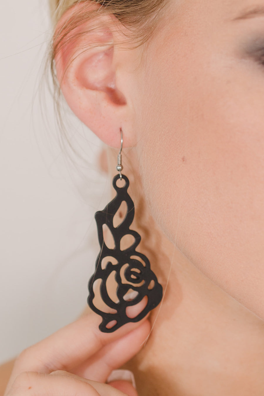 zoom, gros plan, vue boucles d'oreilles rose japonaise modèle long, couleur noir. Portées par mannequin dorine gaudin. Attache dormeuse en acier inoxydable. Silicone, marque française, ladygum, bijoux fantaisies en silicone. Style fleur, floral, nature, romantique, pendantes, longues. Résistante à l'eau/à la chaleur/à la lumière. Souple, léger, original.