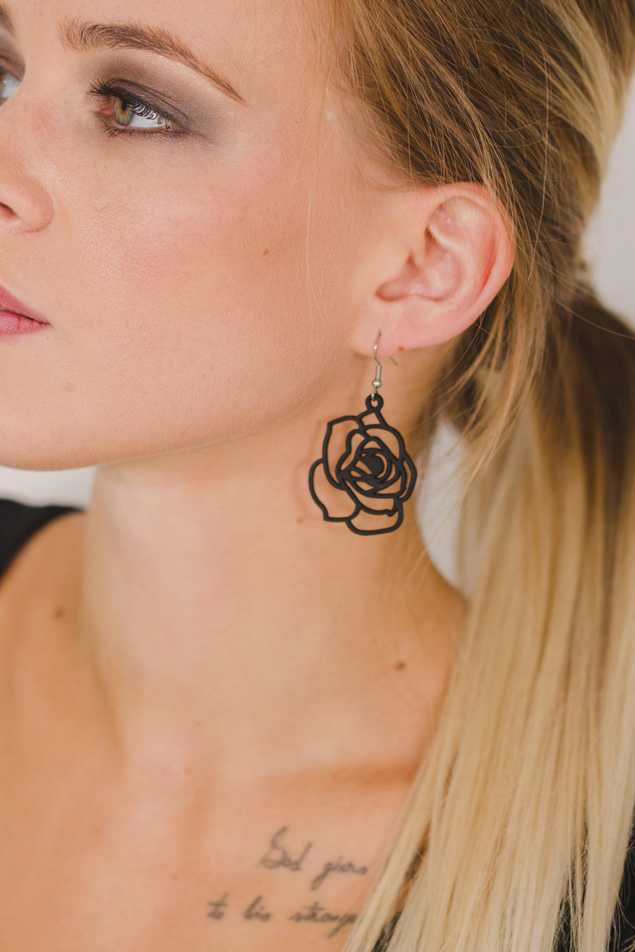 zoom, vue gros plan, paire de boucles d'oreilles rose, couleur noir. Portées par mannequin Dorine Gaudin. Bijoux fantaisies en silicone, marque française, créateurs, designers. Style fleur, floral, nature, amour, pétale. Attache dormeuse en acier inoxydable. Minimisant les allergies, résistant à l'eau/à la chaleur/à la lumière, souple, léger. Cadeau original.