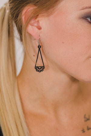 zoom, vue gros plan, paire de boucles d'oreilles dentelle, couleur noir. Portées par mannequin Dorine Gaudin. Bijoux fantaisies en silicone, marque française, créateurs, designers. Style pendante, géométrique, graphique, féminin, minimaliste, motif. Attache dormeuse en acier inoxydable. Minimisant les allergies, résistant à l'eau/à la chaleur/à la lumière, souple, léger. Cadeau original.