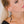 zoom, vue gros plan, paire de boucles d'oreilles primavera, couleur noir. Portées par mannequin Dorine Gaudin. Bijoux fantaisies en silicone, marque française, créateurs, designers. Style longue, pendante, fleur, nature. Attache dormeuse en acier inoxydable. Minimisant les allergies, résistant à l'eau/à la chaleur/à la lumière, souple, léger. Cadeau original.