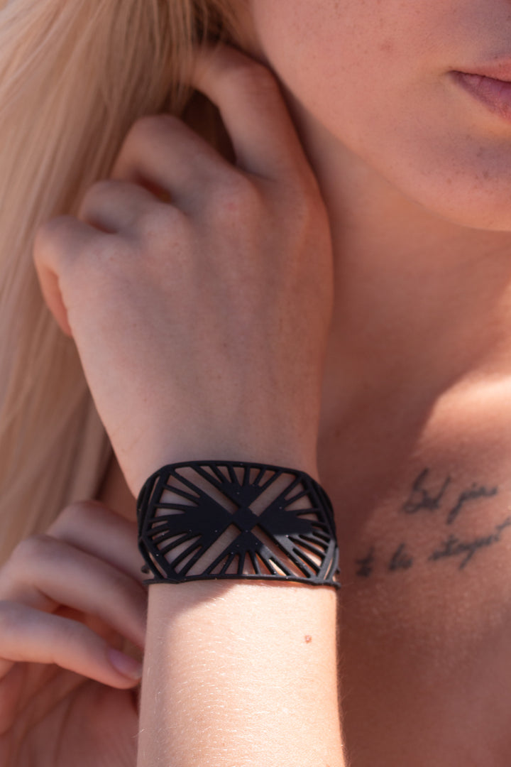 zoom, vue gros plan, bracelet charleston, couleur noir. Vue taille réelle, porté sur poignet par mannequin Dorine Gaudin. Bijoux fantaisies en silicone, ladygum, marque française, créateurs, designers. Style manchette femme, montre, art déco, vintage, rétro, graphique, géométrique. Léger, souple, longueur réglable, bracelet ajustable, fermoir en T, résistant à l'eau, à la chaleur, à la lumière, minimisant les allergies. Cadeau original.