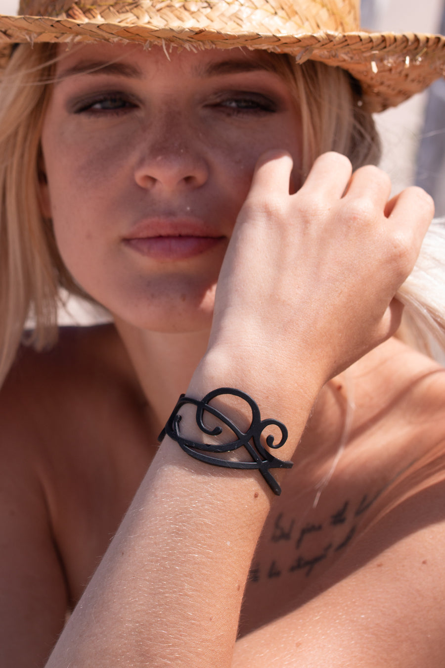 zoom, vue gros plan, bracelet courbe, couleur noir. Vue taille réelle, porté sur poignet par mannequin Dorine Gaudin. Bijoux fantaisies en silicone, ladygum, marque française, créateurs, designers. Style nature, manchette femme, fleur, rond, cercle, tourbillon, abstrait, contemporain. Léger, souple, longueur réglable, bracelet ajustable, fermoir en T, résistant à l'eau, à la chaleur, à la lumière, minimisant les allergies. Cadeau original.