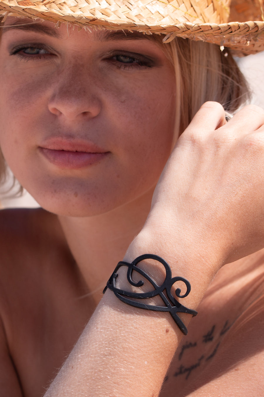 zoom, vue gros plan, bracelet courbe, couleur noir. Vue taille réelle, porté sur poignet par mannequin Dorine Gaudin. Bijoux fantaisies en silicone, ladygum, marque française, créateurs, designers. Style nature, manchette femme, fleur, rond, cercle, tourbillon, abstrait, contemporain. Léger, souple, longueur réglable, bracelet ajustable, fermoir en T, résistant à l'eau, à la chaleur, à la lumière, minimisant les allergies. Cadeau original.