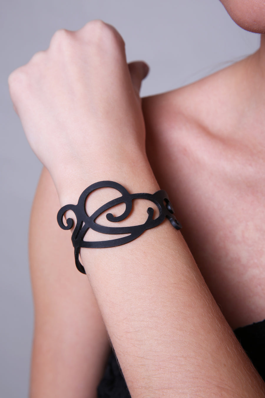 vue gros plan, taille réelle, bracelet courbe, couleur noir, en silicone, porté par mannequin, Alla.. Bijoux fantaisies, bracelet fantaisie en silicone, ladygum, marque française, créateurs, designers. Style minimaliste, vague, fleur, nature, abstrait, féminin, manchette. Bijou effet tatoo. Longueur réglable, bracelet ajustable, fermoir en T, léger, souple, résistant à l'eau, à la chaleur, à la lumière, minimisant les allergies. Idée cadeau