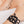 zoom, vue gros plan, bracelet hibiscus, couleur noir. Vue taille réelle, porté sur poignet par mannequin Dorine Gaudin. Bijoux fantaisies en silicone, ladygum, marque française, créateurs, designers. Style manchette femme, nature, fleur, floral, exotique, tropical, île, feuilles, plage. Léger, souple, longueur réglable, bracelet ajustable, fermoir en T, résistant à l'eau, à la chaleur, à la lumière, minimisant les allergies. Cadeau original.