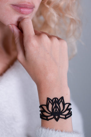 vue gros plan, détails, bracelet mantra, noir, silicone, porté sur mannequin, dorine gaudin. Ladygum, bijoux fantaisies, créateurs, designers, marque française. Style manchette, zen, fleur, floral, indien, nature, feuilles, lotus. Souple, léger, minimisant les allergies, longueur réglable, fermoir en T, résistant à l'eau, à la chaleur, à la lumière.