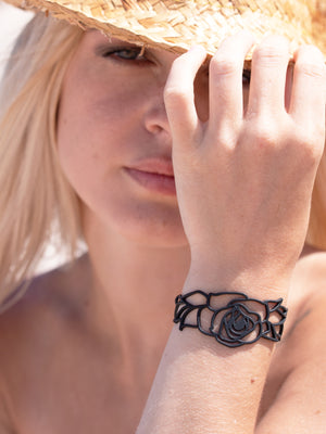 zoom, vue gros plan, bracelet rose, couleur noir. Vue taille réelle, porté sur poignet par mannequin Dorine Gaudin. Bijoux fantaisies en silicone, ladygum, marque française, créateurs, designers. Style nature, manchette femme, fleur, amour, romantique, feuille. Léger, souple, longueur réglable, bracelet ajustable, fermoir en T, résistant à l'eau, à la chaleur, à la lumière, minimisant les allergies. Cadeau original.