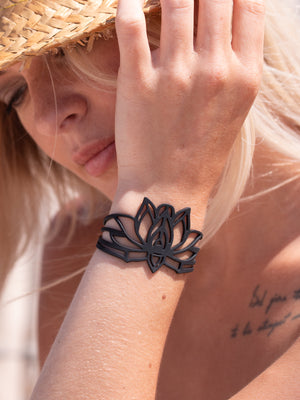zoom, vue gros plan, bracelet mantra, couleur noir. Vue taille réelle, porté sur poignet par mannequin Dorine Gaudin. Bijoux fantaisies en silicone, ladygum, marque française, créateurs, designers. Style nature, manchette femme, fleur, floral, zen, lotus, nénuphar, yoga, feuille, plante. Léger, souple, longueur réglable, bracelet ajustable, fermoir en T, résistant à l'eau, à la chaleur, à la lumière, minimisant les allergies. Cadeau original.