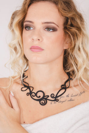 zoom, vue gros plan, collier courbe, couleur noir, dispo en turquoise/bleu/vert. Vue taille réelle, porté par mannequin dorine gaudin. Bijoux fantaisies en silicone, ladygum, marque française, créateurs, designers. Style fleur, nature, floral, rond, cercle, boucle, tourbillon, absrait. Léger, souple, résistant à l'eau/à la chaleur/à la lumière. Collier ajustable, longueur réglable, fermoir en T. Cadeau original.
