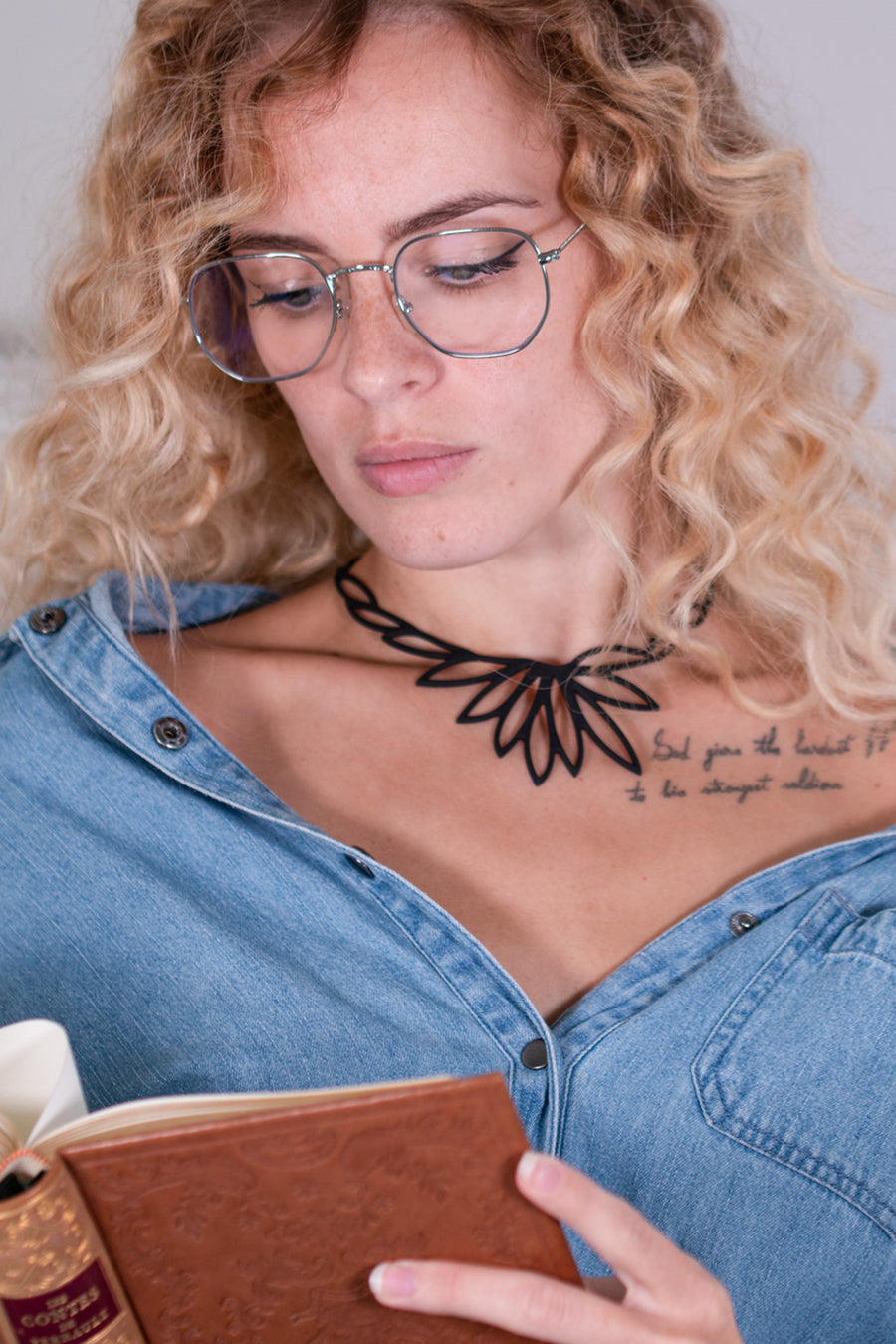 vue taille réelle, collier lotus porté sur mannequin, dorine gaudin. Silicone, noir, ladygum, marque française, bijoux fantaisies, créateurs, designers. Style fleur, floral, feuille, zen, minimaliste. Léger, souple, longueur réglable, ajustable, minimisant les allergies, résistant à l'eau, à la chaleur. Modèle lotus.