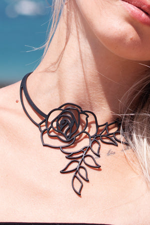 zoom, vue gros plan, collier rose, couleur noir. Vue taille réelle, porté par mannequin dorine gaudin. Bijoux fantaisies en silicone, ladygum, marque française, créateurs, designers. Style plongeant, pendant, fleur, feuilles, nature, floral, amour, romantique, fleur éternelle. Léger, souple, résistant à l'eau/à la chaleur/à la lumière. Collier ajustable, longueur réglable, fermoir en T. Cadeau original.