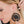 zoom, vue gros plan, paire de boucles d'oreilles triptic, couleur noir. Portées par mannequin Dorine Gaudin. Bijoux fantaisies en silicone, marque française, créateurs, designers. Style créole, lune, étoile, croissant, cercle, rond, lunaire, astronomie. Attache dormeuse en acier inoxydable. Minimisant les allergies, résistant à l'eau/à la chaleur/à la lumière, souple, léger. Cadeau original.