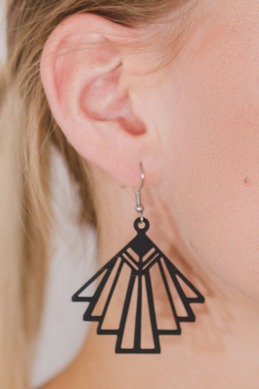 zoom, vue gros plan, paire de boucles d'oreilles charleston, couleur noir. Portées par mannequin Dorine Gaudin. Bijoux fantaisies en silicone, marque française, créateurs, designers. Style éventail, art déco, rétro, géométrique, graphique, moderne, contemporain. Attache dormeuse en acier inoxydable. Minimisant les allergies, résistant à l'eau/à la chaleur/à la lumière, souple, léger. Cadeau original.
