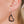 zoom, vue gros plan, paire de boucles d'oreilles love 2 love, couleur noir. Portées par mannequin Dorine Gaudin. Bijoux fantaisies en silicone, marque française, créateurs, designers. Style minimaliste, coeur, amour, courte, petite, créole. Attache dormeuse en acier inoxydable. Minimisant les allergies, résistant à l'eau/à la chaleur/à la lumière, souple, léger. Cadeau original.