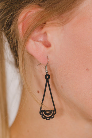 zoom, vue gros plan, paire de boucles d'oreilles dentelle, couleur noir. Portées par mannequin Dorine Gaudin. Bijoux fantaisies en silicone, marque française, créateurs, designers. Style pendante, géométrique, graphique, féminin, minimaliste, motif. Attache dormeuse en acier inoxydable. Minimisant les allergies, résistant à l'eau/à la chaleur/à la lumière, souple, léger. Cadeau original.