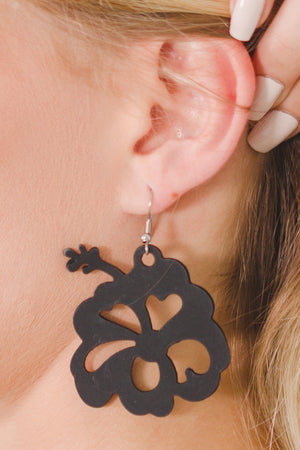 zoom, vue gros plan, paire de boucles d'oreilles hibiscus, couleur noir. Portées par mannequin Dorine Gaudin. Bijoux fantaisies en silicone, marque française, créateurs, designers. Style tropical, fleur, floral, nature, île, exotique, jungle, plage, mer. Attache dormeuse en acier inoxydable. Minimisant les allergies, résistant à l'eau/à la chaleur/à la lumière, souple, léger. Cadeau original.