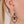 zoom, vue gros plan, boucles d'oreilles Nymphéa, couleur noir, portées sur mannequin Dorine. Attache dormeuse en acier inoxydable. Bijoux fantaisies, marque française, créateurs, designers. Petit modèle, style minimaliste, losange, pampilles, fleurs, géométrique. Silicone, souple, léger, minimisant les allergies, résistant à l'eau/à la chaleur/à la lumière. Idée cadeau original.