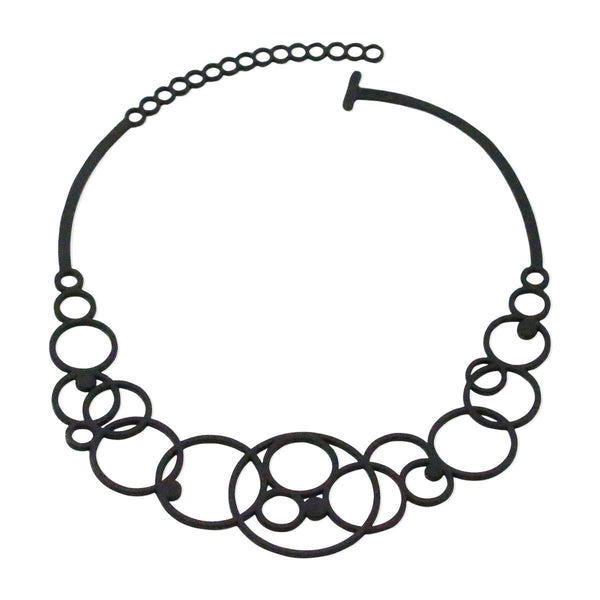 vue collier disco, à plat, en entier, fermoir en T.  Ladygum, bijoux fantaisies, marque française, créateurs, designers. Silicone, disponible en noir. Style rond, cercle, bulle, années 70, seventies, hippie. Minimisant les allergies, léger, souple, longueur réglable, bijou ajustable, résistant à l'eau et à la chaleur. Modèle disco.