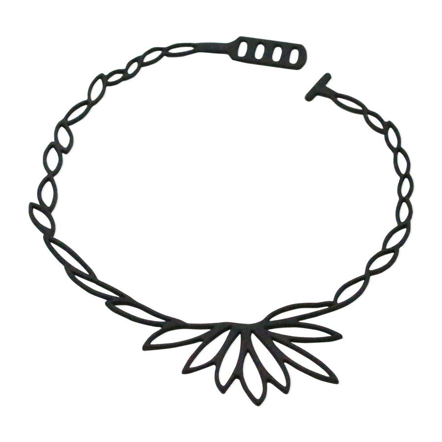vue collier lotus, à plat, en entier, fermoir en T. Silicone, noir, ladygum, marque française, bijoux fantaisies, créateurs, designers. Style fleur, floral, feuille, zen, minimaliste. Léger, souple, longueur réglable, ajustable, minimisant les allergies, résistant à l'eau, à la chaleur. Modèle lotus.